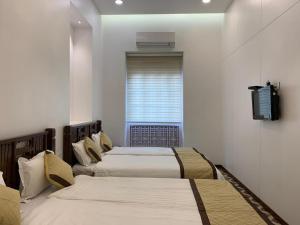 a room with three beds and a tv on a wall at Carlton Hotel Mumbai - Behind Taj Mahal Palace Colaba Mumbai in Mumbai