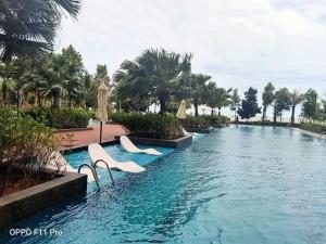 einen Pool mit Stühlen und Palmen in einem Resort in der Unterkunft AK Homes in Kuantan