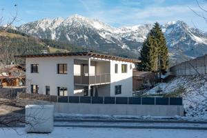 een wit huis met besneeuwde bergen op de achtergrond bij Appartement Sophie in Söll