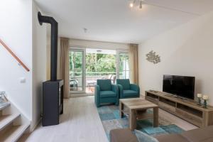 a living room with a blue chair and a television at Appartement - Kaapduinseweg 13 Dishoek M Luxe 6 personen in Koudekerke