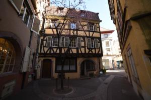 a building with a tree in the middle of a street at Gite Bim Maidala in Colmar