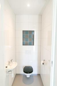 a bathroom with a black toilet and a sink at 8p Luxe bungalow met serre in s-Gravenzande
