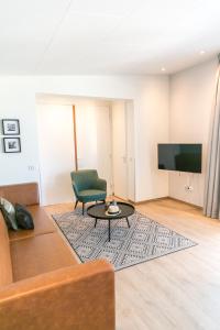 een woonkamer met een bank, een tafel en een tv bij 8p Luxe bungalow met serre in 's-Gravenzande