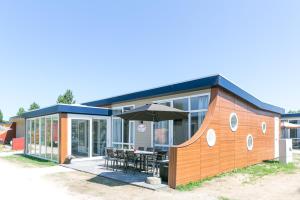 een klein huis met een tafel en een paraplu bij 8p Luxe bungalow met serre in 's-Gravenzande