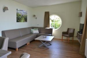 a living room with a couch and a table at Bungalow 14 personen in s-Gravenzande