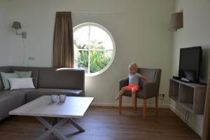 a baby sitting in a chair in a living room at Bungalow 8 personen in s-Gravenzande