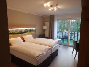 um quarto de hotel com uma cama e uma varanda em Hotel garni Haaster Krug Otte em Großenkneten