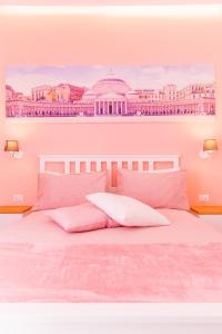 een bed met roze kussens en een schilderij van een gebouw bij Casa GALU' in Napels