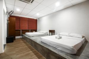 2 Betten in einem Zimmer mit weißen Wänden und Holzböden in der Unterkunft UrbanStay Industrial in Ipoh