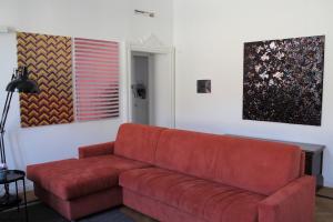 un sofá rojo en una sala de estar con pinturas en Palazzo della Torre Elegant Apartment in Como, en Como