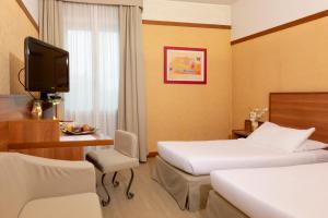 una camera d'albergo con due letti e una televisione di SHG Hotel Bologna a Zola Predosa