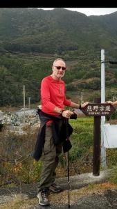 a woman standing next to a sign on a mountain at Kumano Kodo Nagano Guesthouse in Tanabe