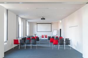 una sala de conferencias con sillas rojas y una pizarra en havenhostel Bremerhaven en Bremerhaven