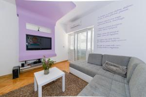a living room with a couch and a tv on a wall at Family & pet friendly apartment Martina in Promajna