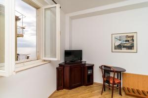 a room with a table and a tv and a window at Villa Odak in Dubrovnik