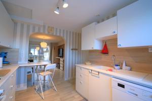 cocina con armarios blancos, mesa y sillas en Appartement de 57m2 vue sur mer et plage, en Le Portel