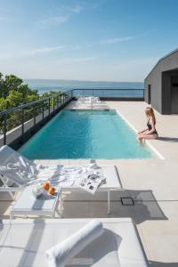 a woman sitting in a swimming pool next to the ocean at briig boutique hotel in Split