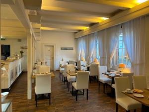 a restaurant with tables and white chairs and windows at Hotel Flensburger Hof in Flensburg