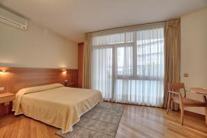 a bedroom with a bed and a desk and a window at PR Rosa Rosae in Santiago de Compostela