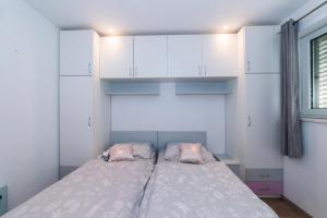 a bedroom with a bed with white cabinets and a window at Apartman IT Vila Vesa Promajna in Promajna