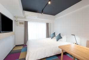 1 dormitorio con cama blanca y mesa de madera en Tokyu Stay Meguro Yutenji, en Tokio