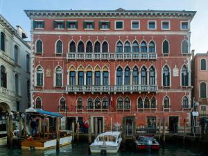 a large red brick building with boats docked in the water at EGO' Boutique Hotel - The Silk Road in Venice