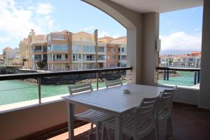 a table and chairs on a balcony with a view of the water at The Boardwalk Accommodation in Gordonʼs Bay