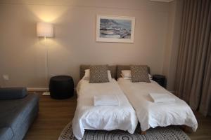 um quarto de hotel com duas camas e um sofá em The Boardwalk Accommodation em Gordonʼs Bay