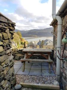 einen Picknicktisch in einer Steinmauer mit Blick auf das Wasser in der Unterkunft Penbryn Holidays, Barmouth in Barmouth