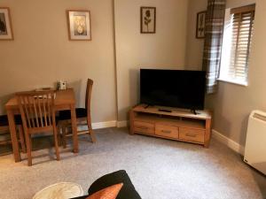 ein Wohnzimmer mit einem TV und einem Esstisch in der Unterkunft Clarabel's Guest House- The Nook in Wombourn