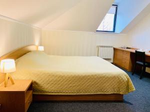 a bedroom with a bed and a desk and a window at Business Hotel Kostroma in Kostroma