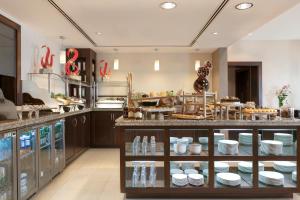 a large kitchen with a counter with dishes on display at Traders Hotel, Abu Dhabi in Abu Dhabi