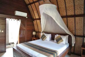 a bedroom with a bed with a canopy at Unzipp Lumbung Gili Trawangan in Gili Trawangan