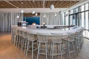 a bar with stools in a room with windows at Falkensteiner Hotel Park Punat in Punat
