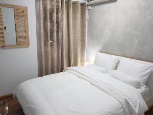 a white bed with white pillows and a window at See&Sun in Ashdod