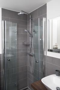 une salle de bain avec une douche en verre avec un lavabo dans l'établissement Hotel Angerland Garni, à Ratingen