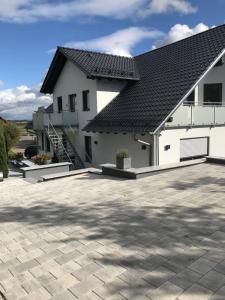 a white house with a black roof and a patio at LUX Ferienwohnungen in Hepbach
