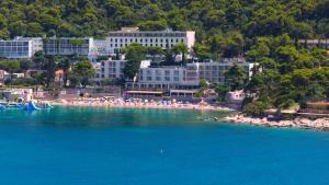 a beach with umbrellas and people in the water at Hotel Vis in Dubrovnik