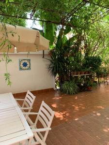 un patio con sillas blancas, una mesa y una pared en Matteo's home, en Donnalucata