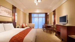 Pokój hotelowy z łóżkiem, biurkiem i telewizorem w obiekcie Wyndham Grand Tianjin Jingjin City w mieście Tiencin