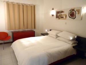 a bedroom with a white bed and a red chair at Casa Julio in Carvoeiro