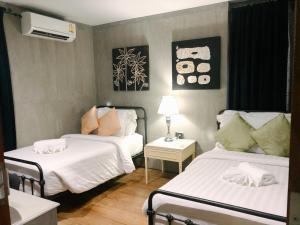 a small room with two beds and a night stand at House Of Passion Amphawa in Amphawa