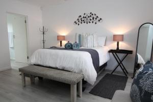 a bedroom with a white bed with a bench and two lamps at Beach Break B&B - Solar Powered in Port Alfred