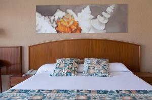 a bed with a wooden headboard and pillows on it at GHT Oasis Park & Spa in Lloret de Mar
