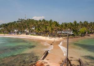 una playa con palmeras y gente en el agua en Sea And River View Mirissa, en Mirissa
