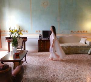 
a woman in a white dress standing in front of a living room at Hotel Palazzo Vitturi in Venice
