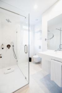 uma casa de banho branca com um chuveiro e um lavatório. em LX SoHo Boutique Hotel by RIDAN Hotels em Lisboa