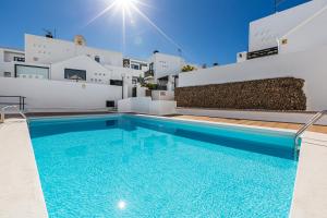 a swimming pool in front of a house with a building at EL ZAFIRO in Puerto del Carmen