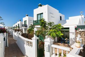 a white building with a fence and palm trees at EL ZAFIRO in Puerto del Carmen