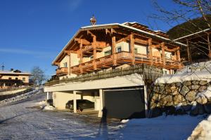 une grande maison en bois avec un garage dans la neige dans l'établissement Landhotel Anna, à Sankt Martin am Tennengebirge